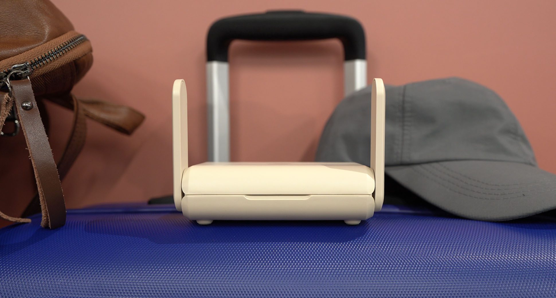 Aircove Go on a suitcase and next to luggage bag